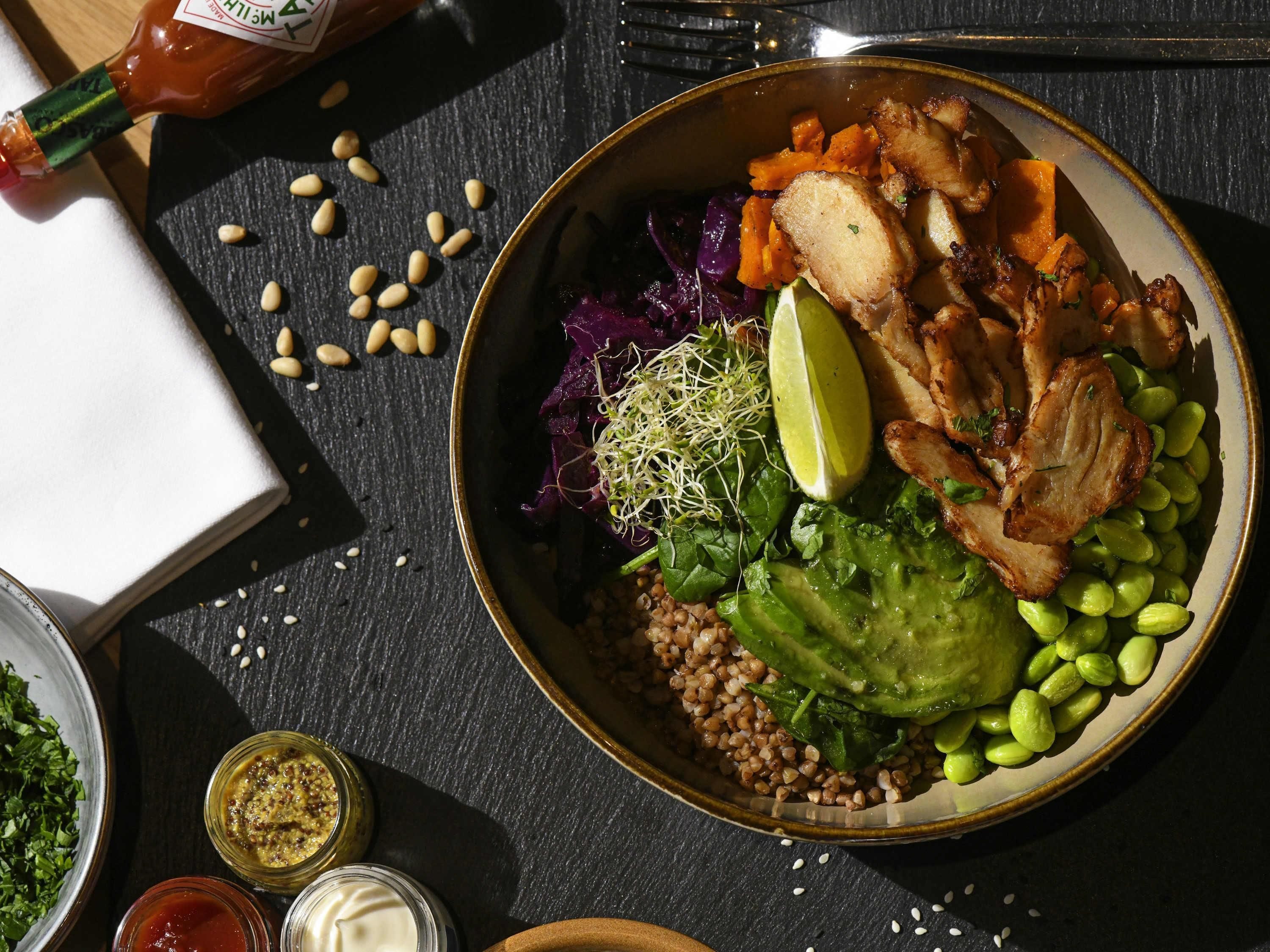 A bowl of food with various ingredients including meat, vegetables, and grains.