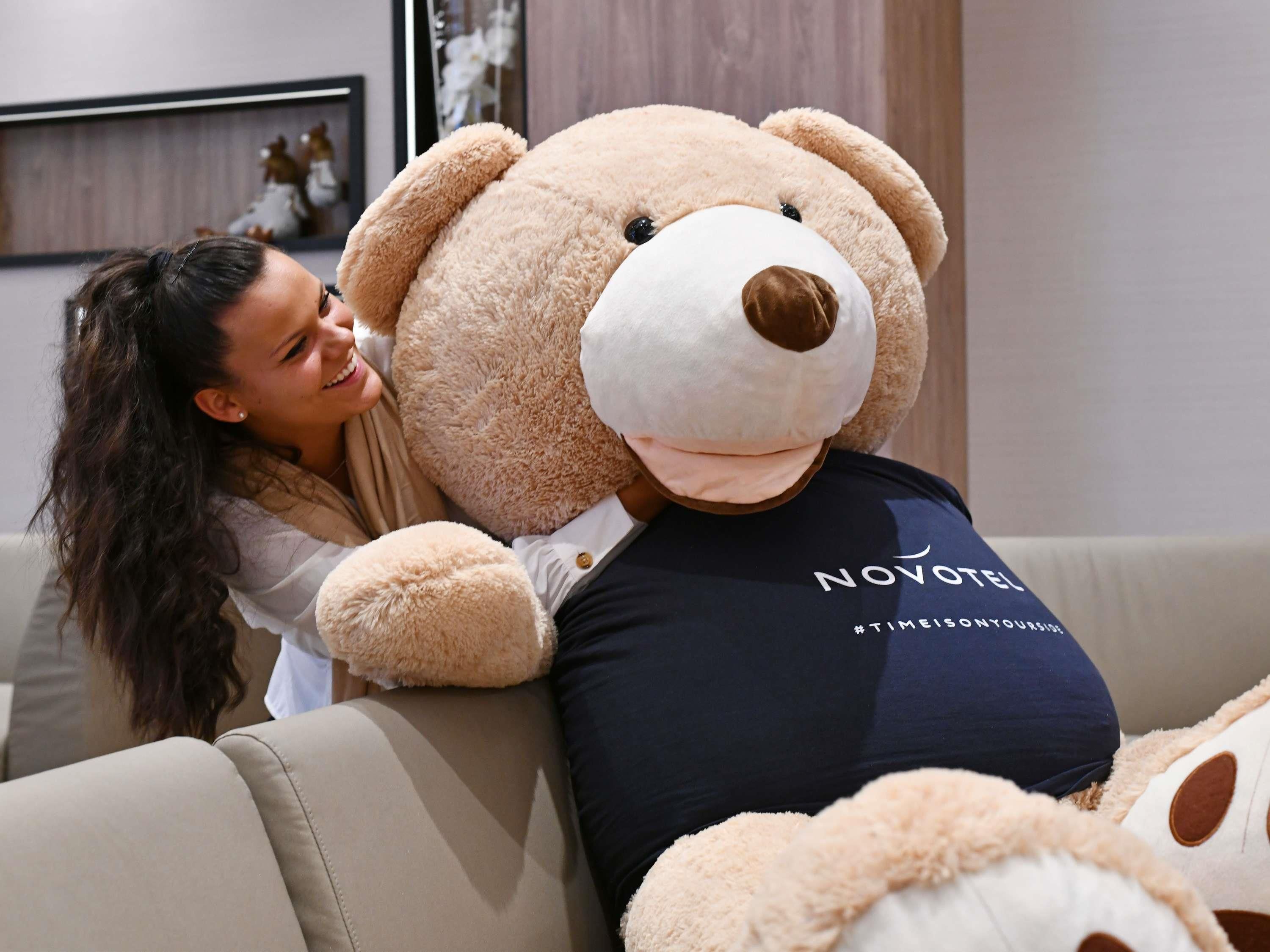 A person sitting on a sofa with a large teddy bear.