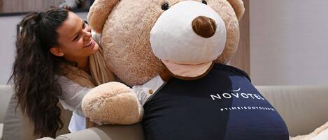 A person sitting on a sofa with a large teddy bear.