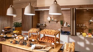 Un ricco buffet della colazione con dolci e pane esposti su tavoli di legno.