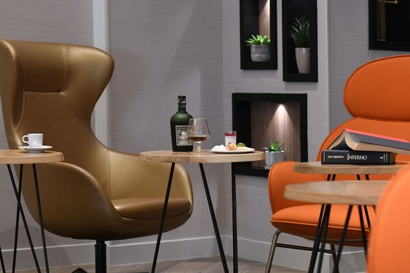 A modern lounge area with leather chairs, a small table with a bottle, a glass, and a book. - Novotel Nice Arenas Aeroport (Nice)