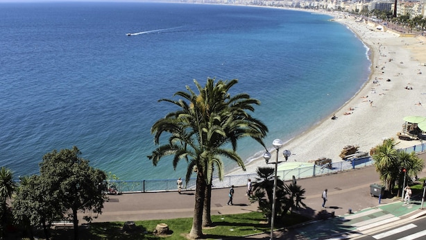 Paesaggio costiero con spiaggia, palme e cielo azzurro limpido.