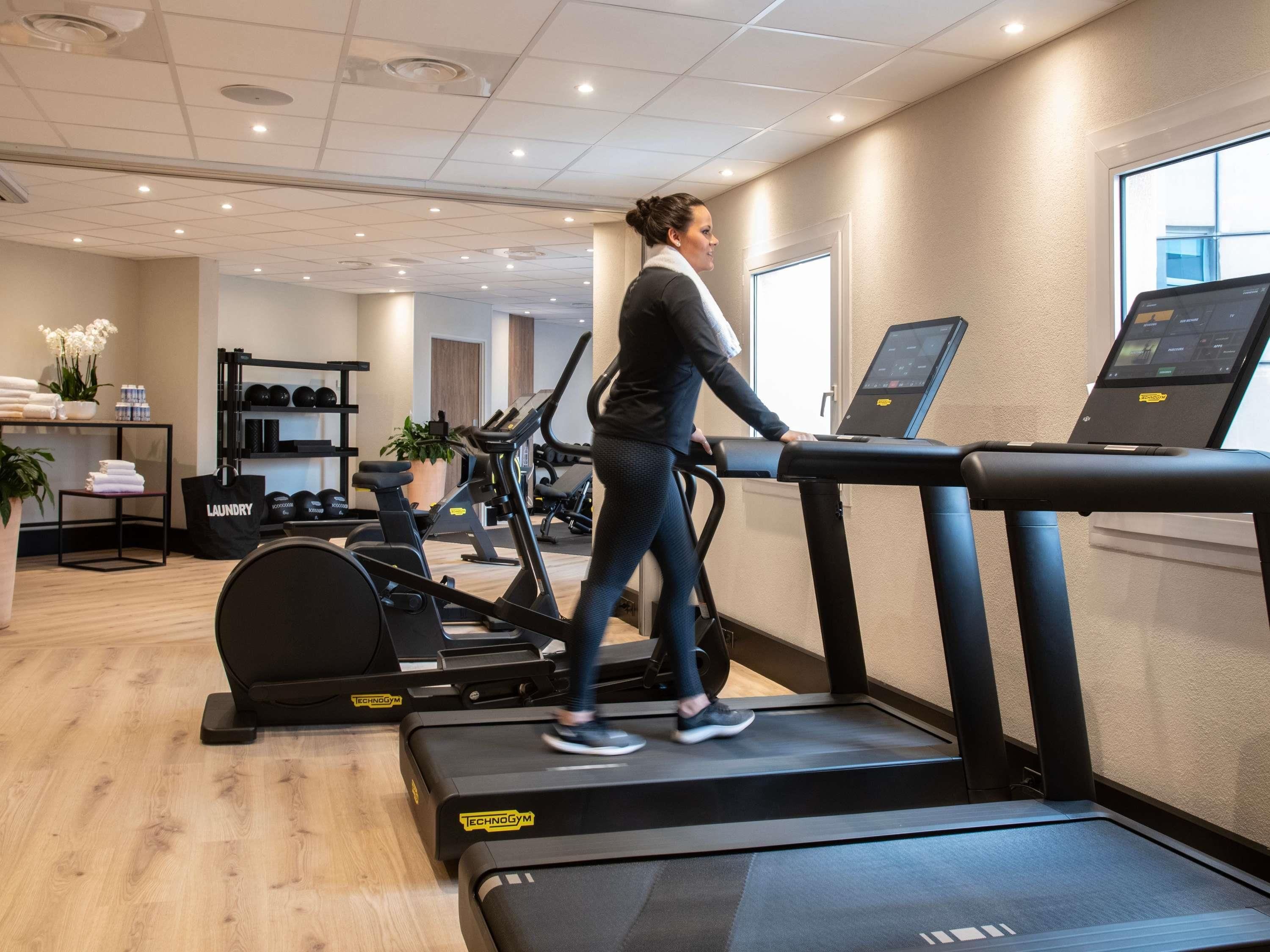 A gym with treadmills, exercise balls, and a digital screen.