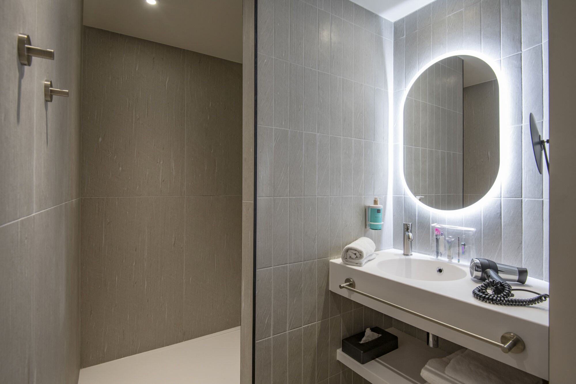A modern bathroom with a large mirror, a sink, and a shower.
