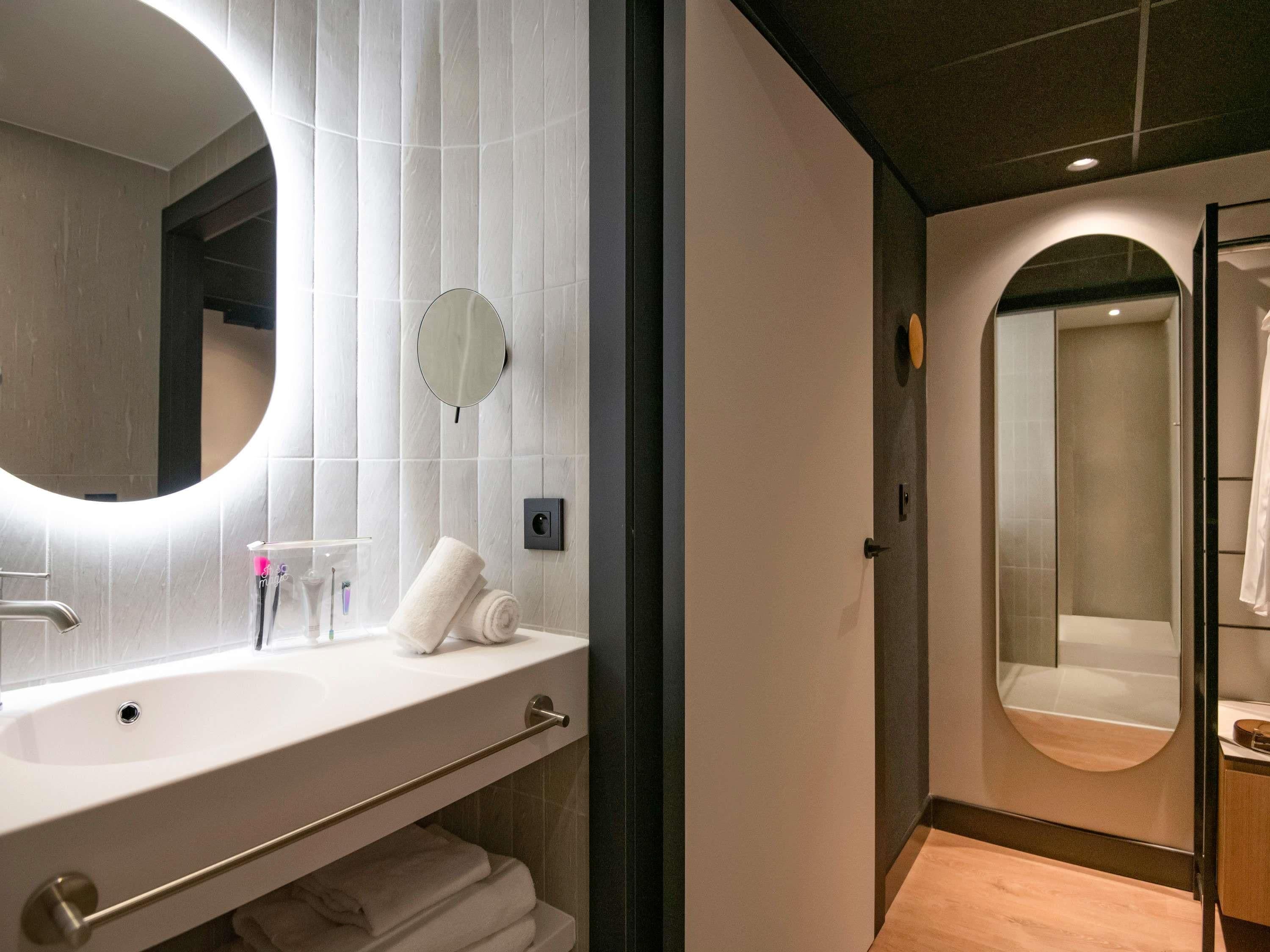 Ein modernes Badezimmer mit einem runden Spiegel, einem Waschbecken und einer Toilette.