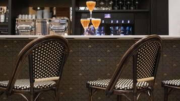 A bar area with a counter, two wicker chairs, a Nespresso machine, and a variety of liquor bottles.