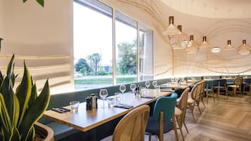 L’intérieur d’un restaurant moderne, avec des tables et des chaises en bois, et une grande fenêtre donnant sur l’extérieur.