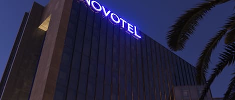 A modern hotel building with a prominent 'NOVOTEL' sign.