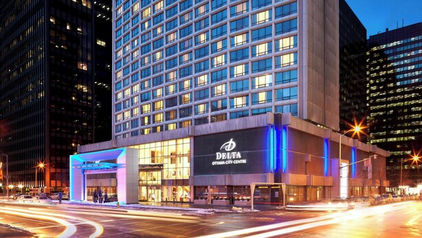 A modern hotel building with a prominent entrance and illuminated signage.