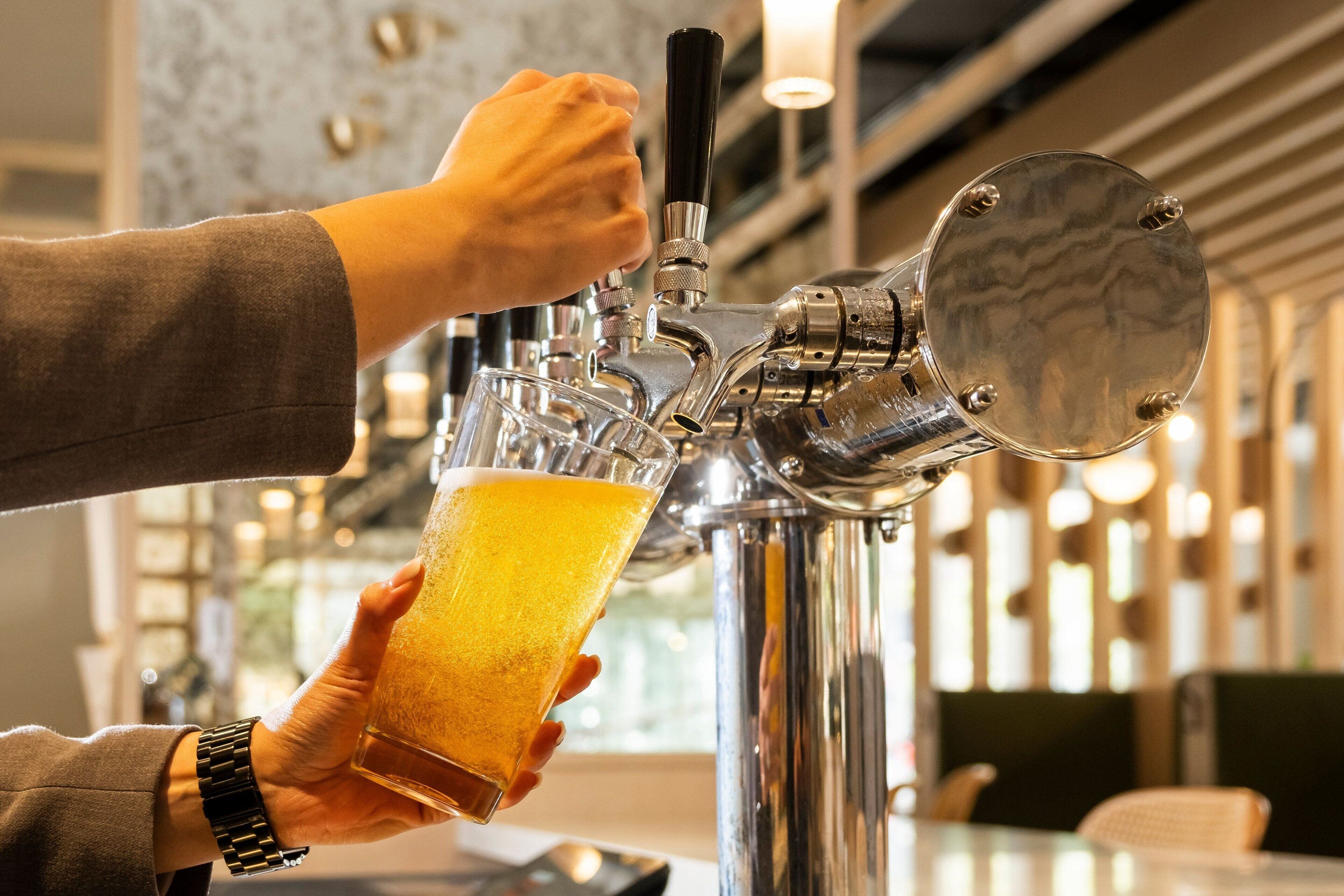 A person pouring beer from a tap into a glass.