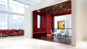 A spacious conference room with a red accent wall, large windows, and a modern ceiling design.
