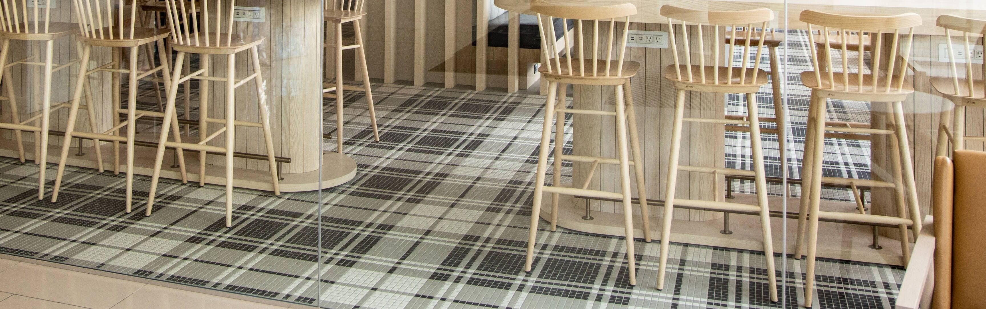 A bar area with multiple wooden stools and a checkered floor pattern.