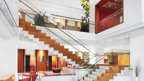 A modern interior with a central staircase, glass railings, and wooden accents.