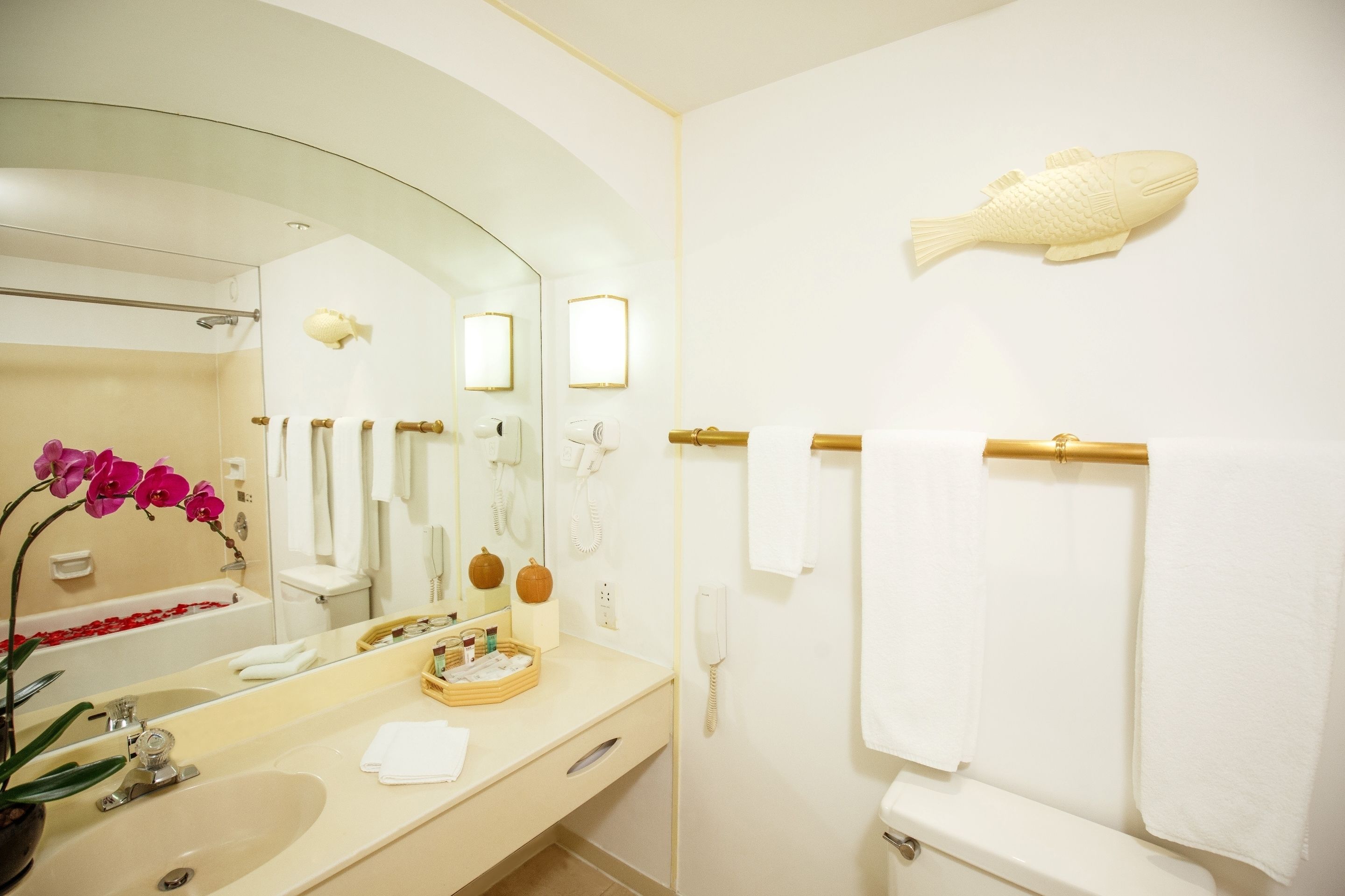 A modern bathroom with a large mirror, a bathtub, a toilet, and a sink.