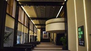 A modern hotel lobby with a long corridor, seating areas, and a prominent green sign on the wall. - Regency Art Hotel Macau (Taipa)