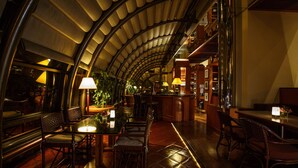 A dimly lit, elegant restaurant with a curved ceiling, wooden flooring, and a bar area. - Regency Art Hotel Macau (Taipa)