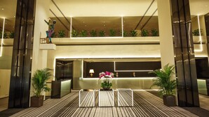 A modern hotel lobby with a reception desk, two floors, and a decorative sculpture. - Regency Art Hotel Macau (Taipa)
