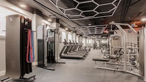 Un gimnasio con cintas de correr, máquinas de pesas y una jaula de sentadillas.
