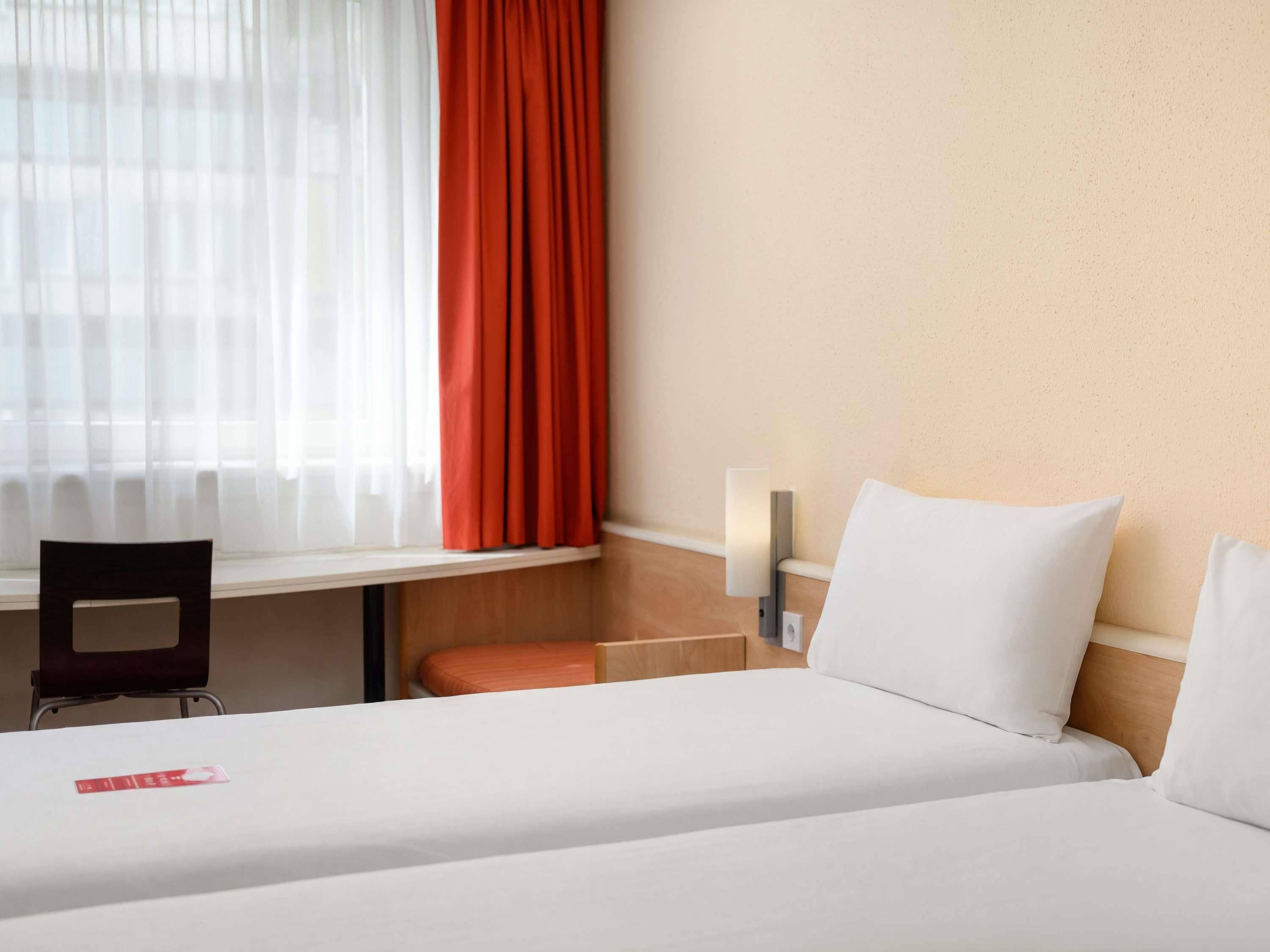 A hotel room with a bed, a desk, and a chair.