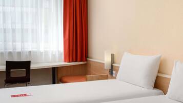 A hotel room with a bed, a desk, and a chair.