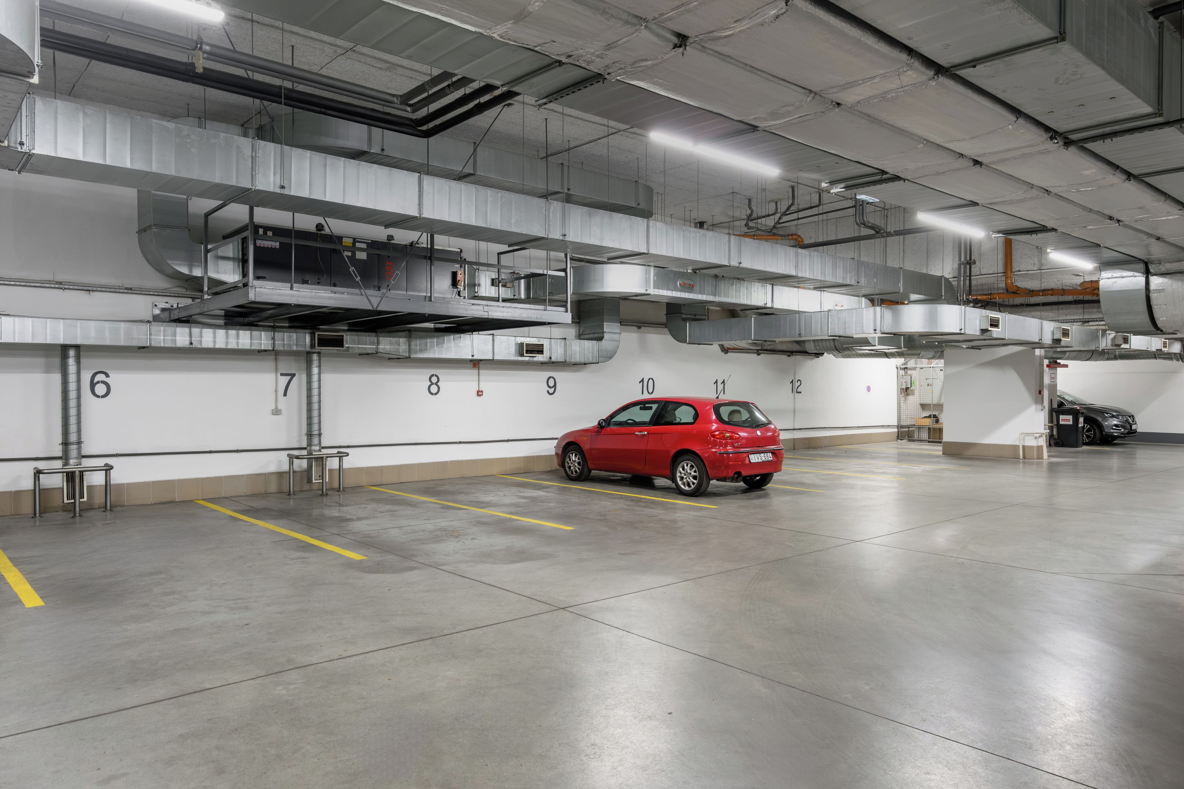 Un parking où une voiture rouge est garée sur une place marquée du numéro 10.