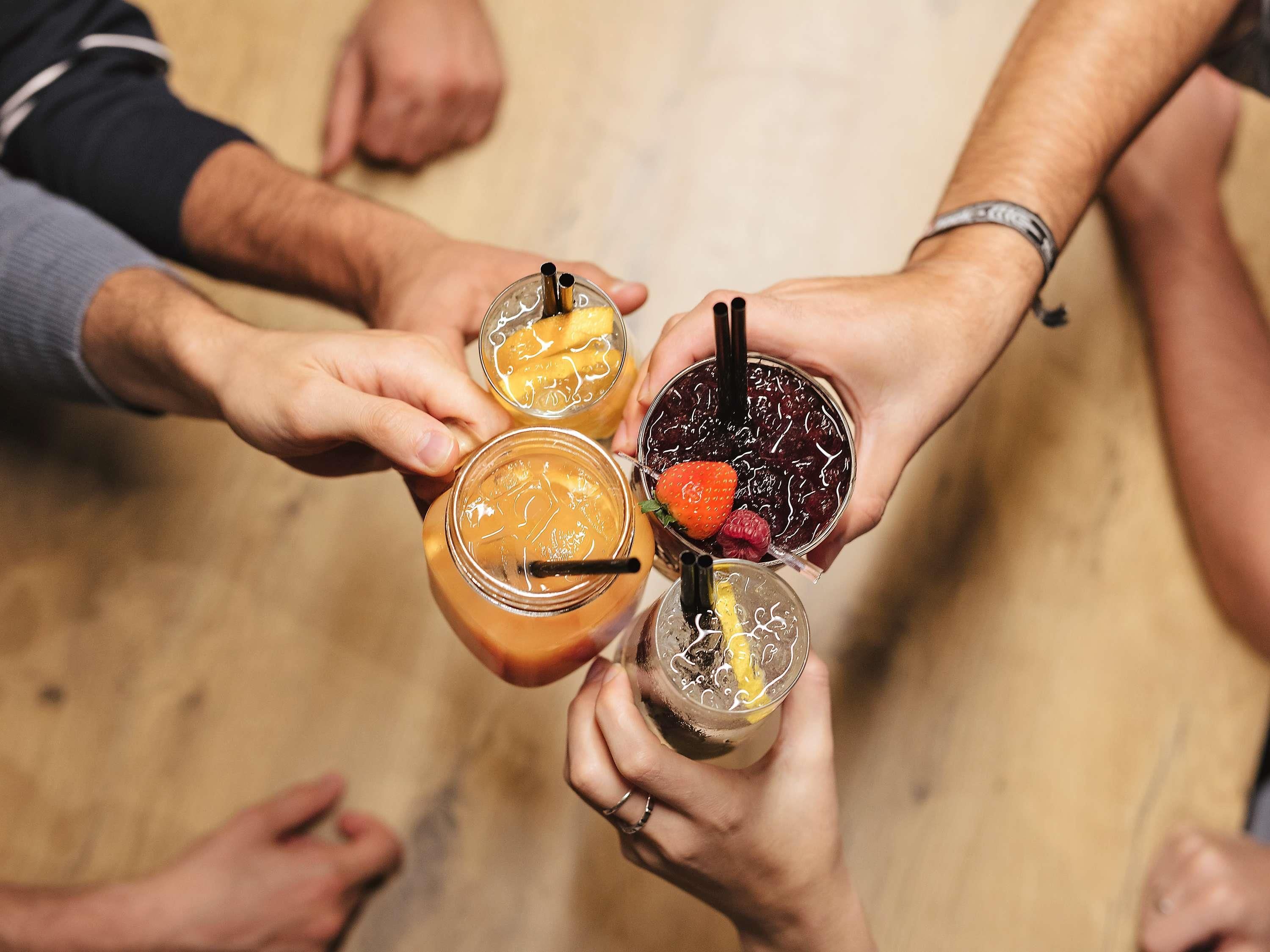 A group of people holding drinks with straws, possibly at a social gathering.