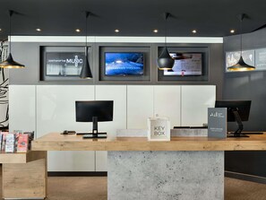 Una recepción de hotel con una caja de llaves, un monitor y cuadros en la pared.