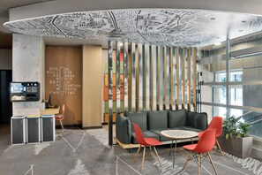 A modern interior with a seating area, a wall with text, and a view through a glass partition. - ibis Budapest City (Budapest)