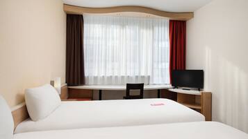 A hotel room with a bed, a desk, a chair, and a television.