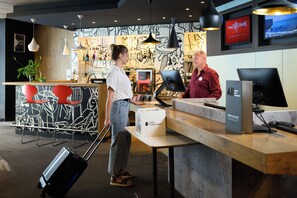 A reception desk with a monitor, a fast check-out sign, and a Coca-Cola refrigerator. - ibis Budapest City (Budapest)