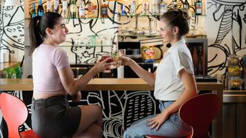 Two individuals seated at a bar with a modern design, holding drinks.