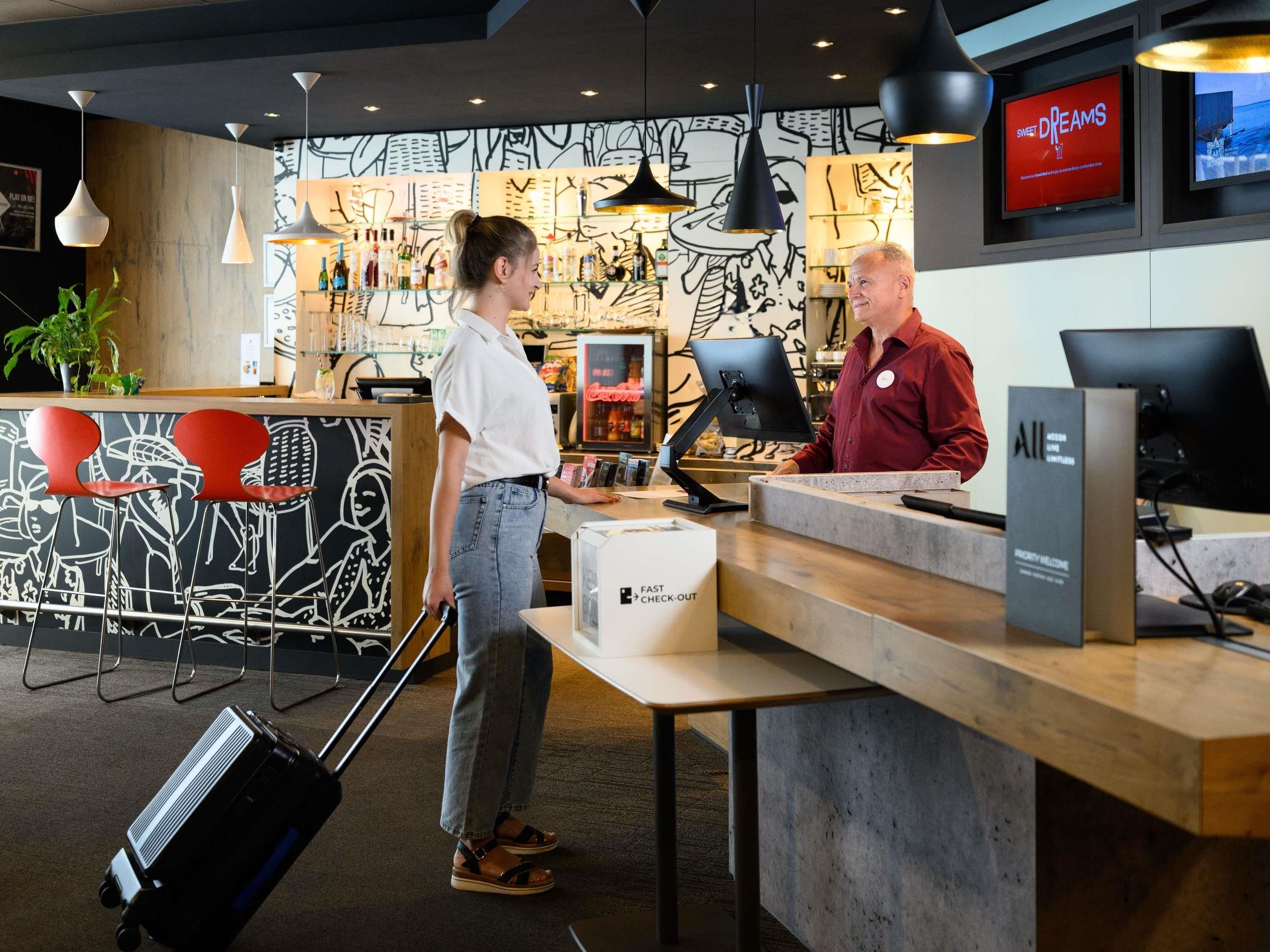 A hotel reception area with a counter, a computer, and a television displaying 'SWEET DREAMS'.