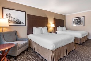 A hotel room with two beds, a sofa, a small table, and two framed pictures on the walls.