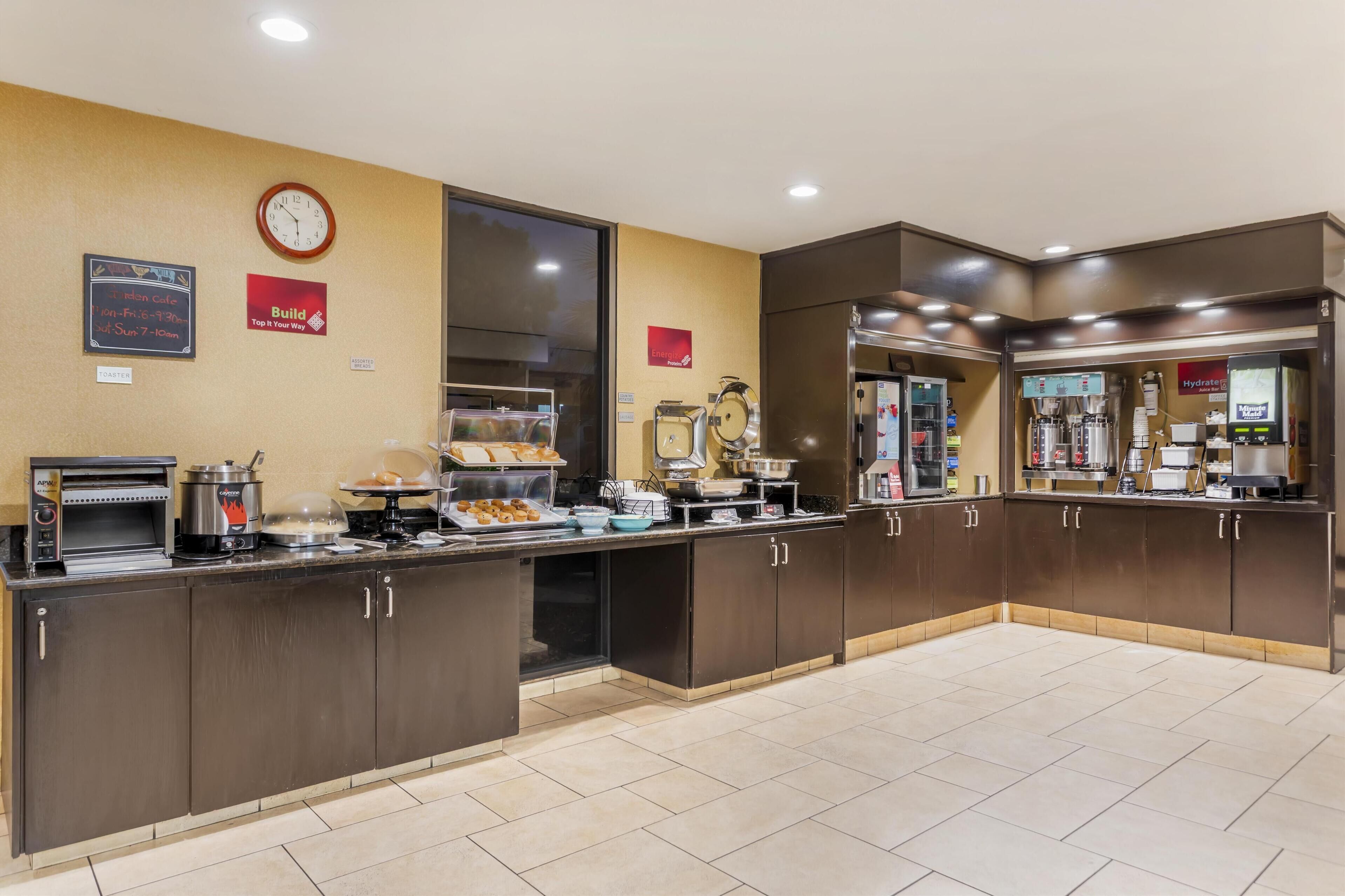 A self-service breakfast area with a toaster, coffee maker, and various food items.