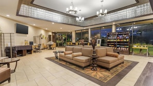A spacious lobby with a large sofa, a dining area, and a reception desk. - Best Western Plus Garden Court Inn (Fremont)