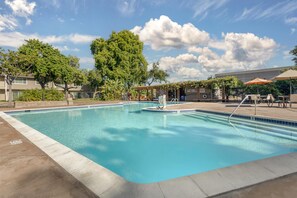 Una piscina al aire libre, sillones reclinables de piscina