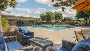 A poolside area with wicker furniture, a pool, and a building with a covered patio in the background. - Best Western Plus Garden Court Inn (Fremont)