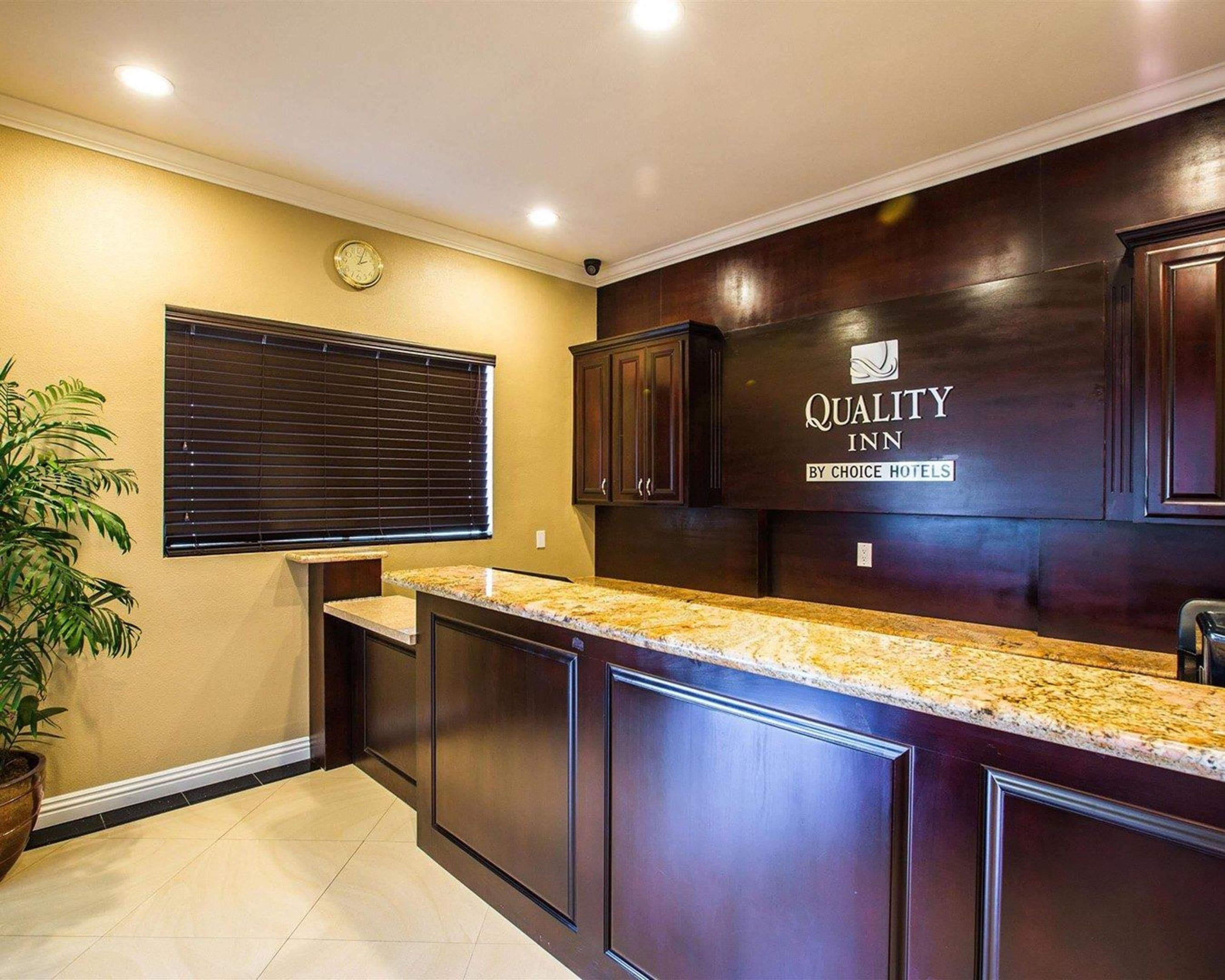 A kitchen with dark wood cabinets, a granite countertop, and a sign for 'Quality Inn by Choice Hotels'.