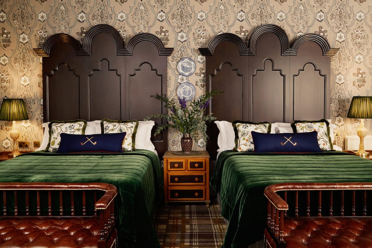 A room with two beds, a wooden nightstand, and a decorative vase.