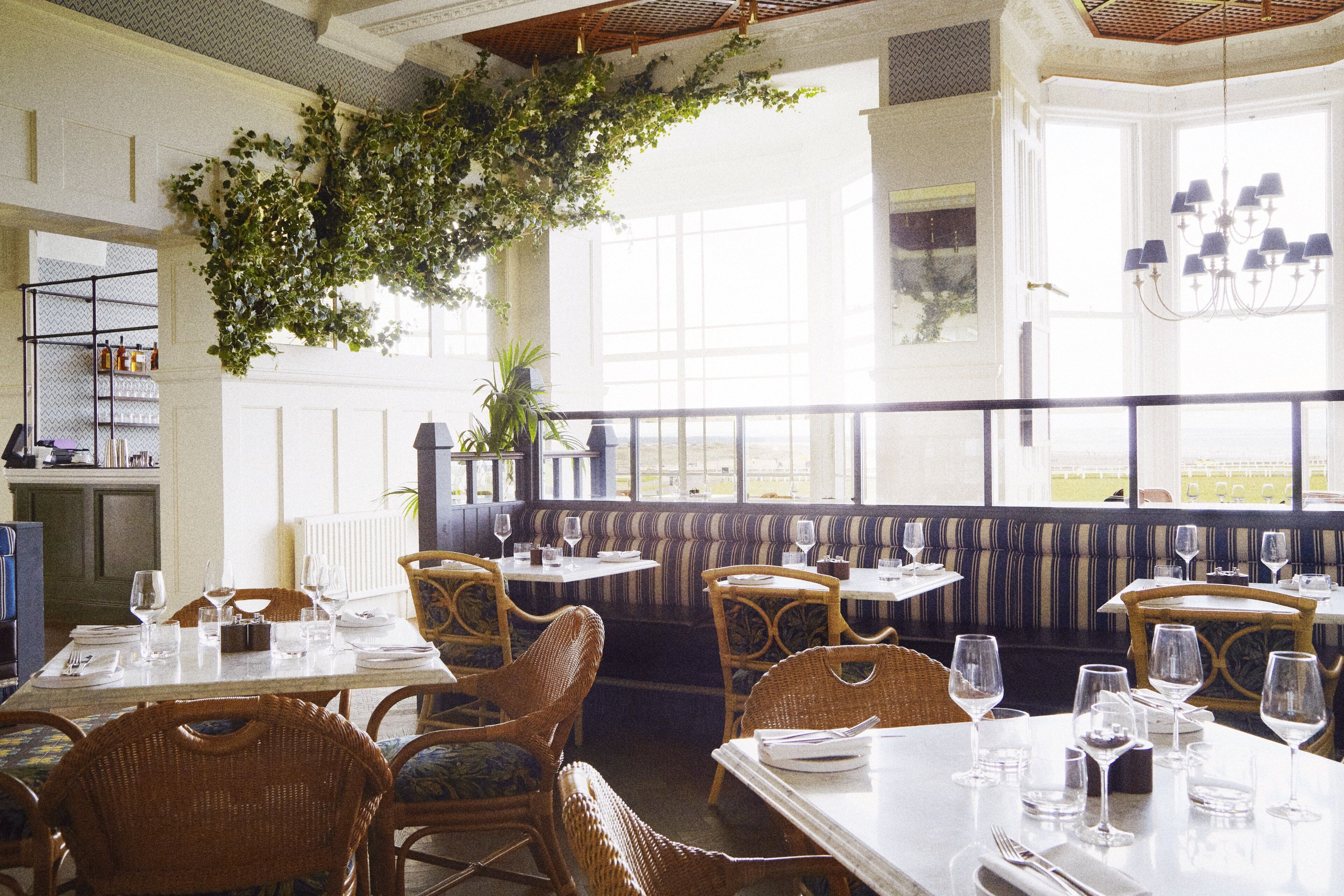 Um restaurante com tetos altos, amplas janelas e diversas opções de assentos, incluindo mesas e cabines.