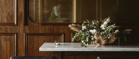 A wooden paneled wall with a window, a marble countertop, and a floral arrangement.