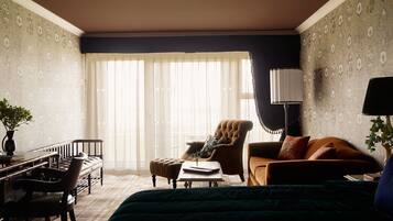A hotel room with a large bed, a sitting area with a sofa and armchair, a desk with a chair, and a large window with sheer curtains.