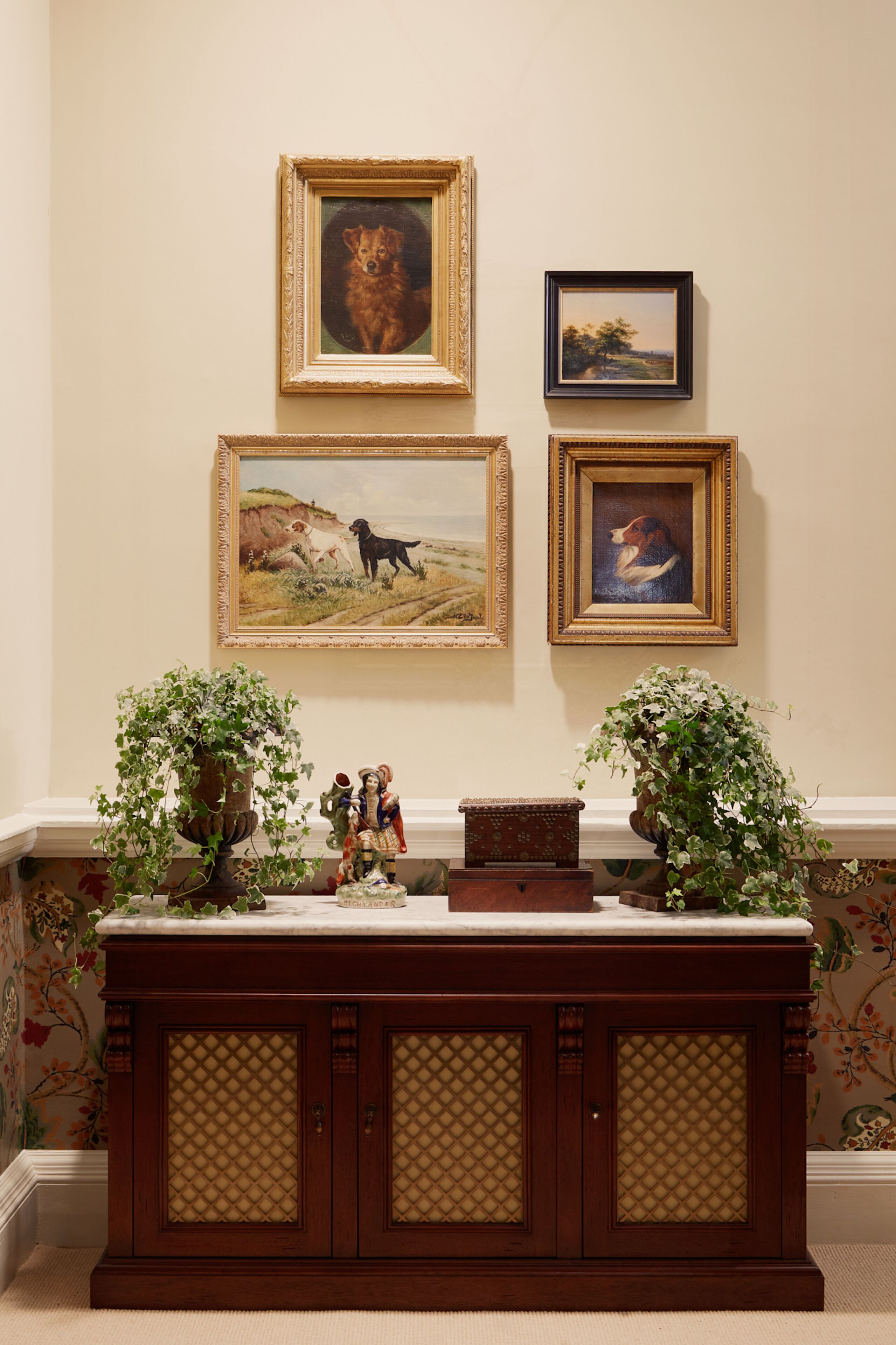 A room with a wooden cabinet, a fireplace, and three framed paintings on the wall.