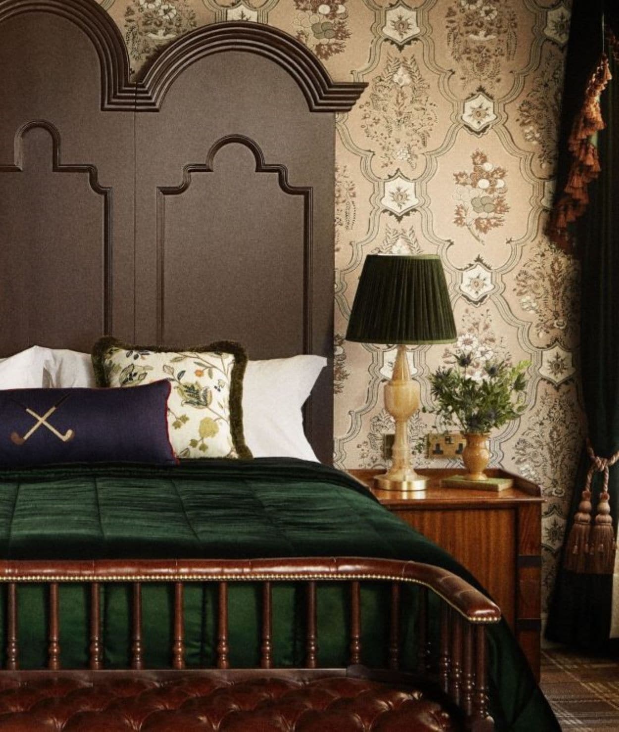 A bed with a dark headboard, a green bedspread, and decorative pillows.