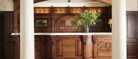 A reception desk with a wooden finish, a marble top, and a framed sign reading "RUSACKS ST ANDREWS."