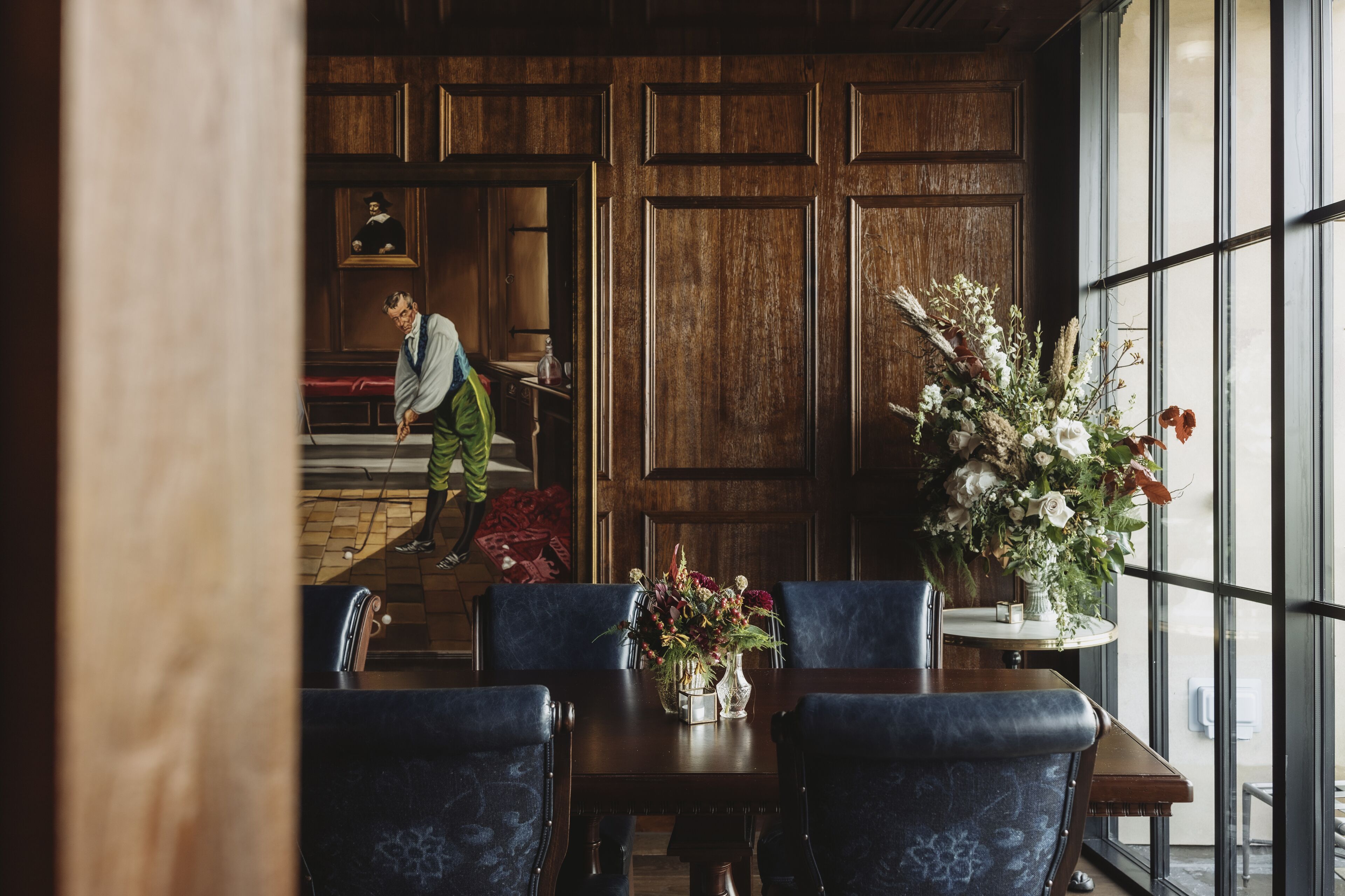 Un comedor con una mesa de madera, sillas tapizadas en azul y un jarrón de flores.