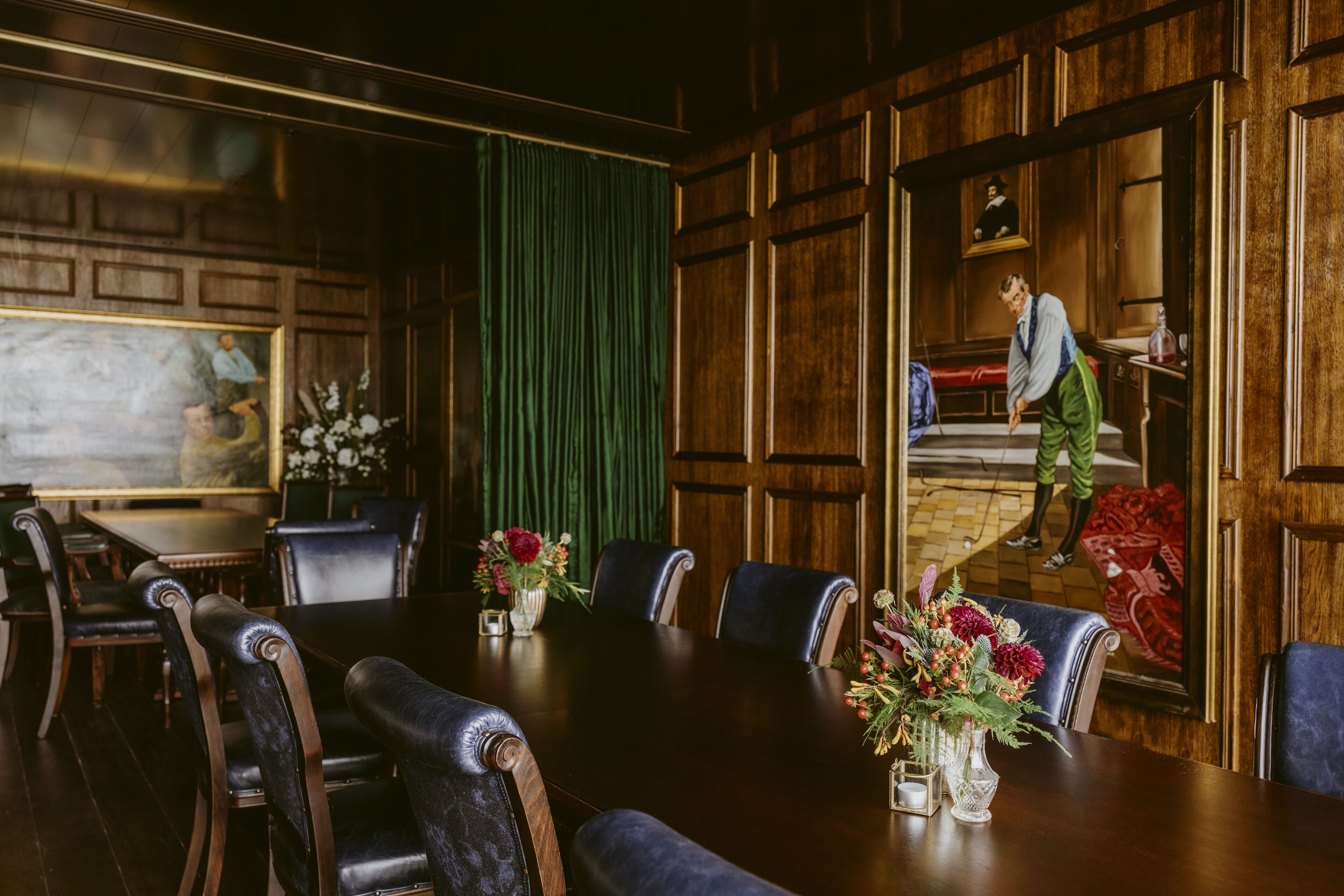 A conference room with a long table, chairs, and a green curtain.