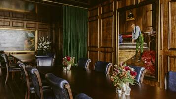 A conference room with a long table, chairs, and a green curtain.