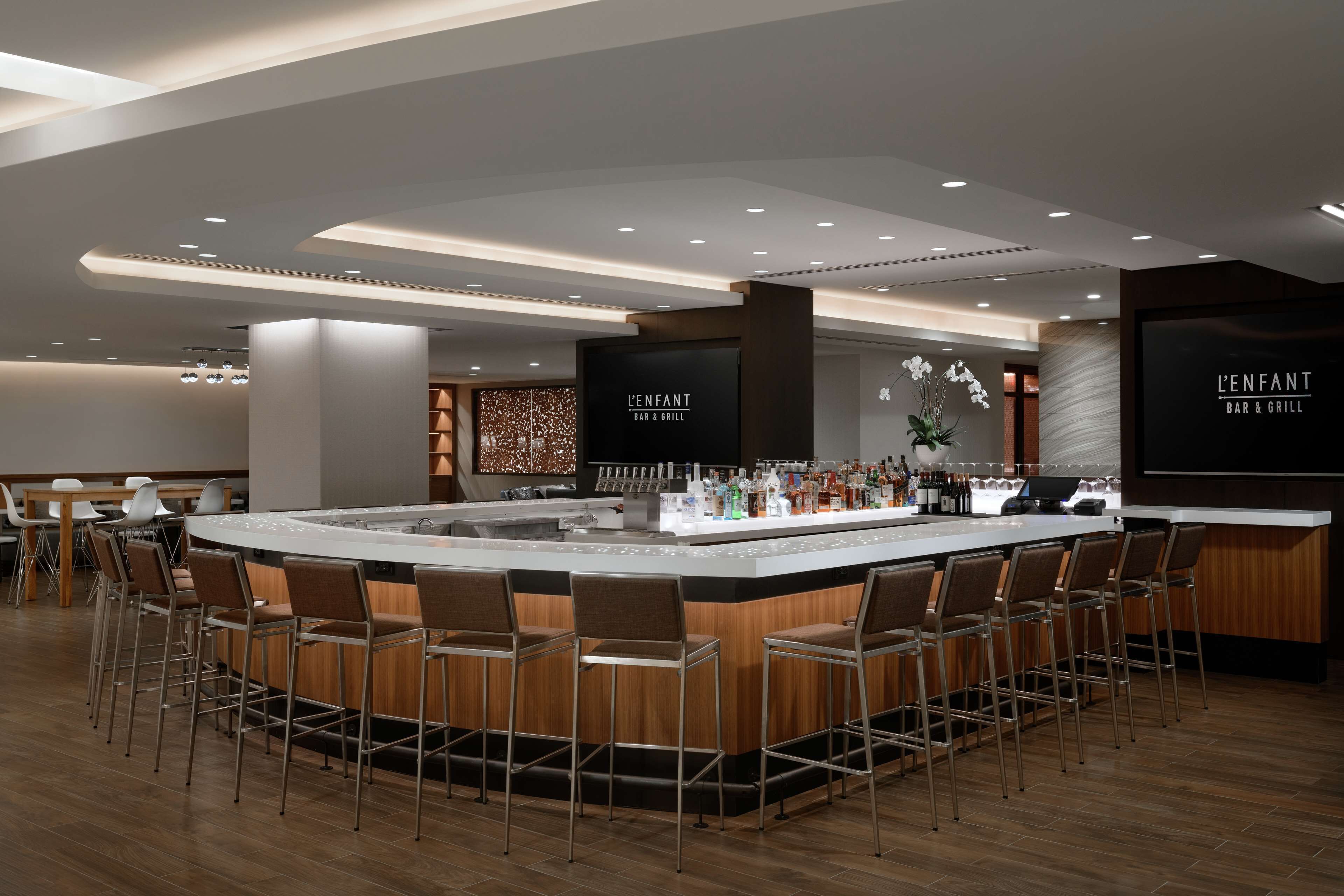 Uma área de bar moderna com ilha central, banquetas e teto bem iluminado.