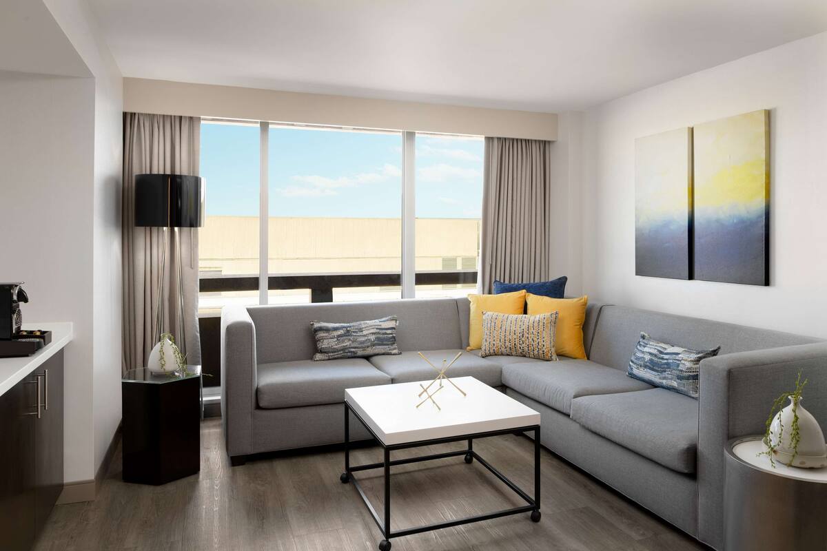 A modern living room with a grey sofa, a white coffee table, and a flat-screen TV.